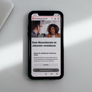 Smartphone mit der geöffneten Terminvereinbarungsseite des Jobcenters.